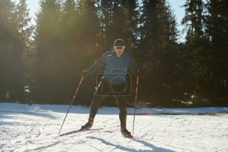 Téléchargez les photos : Ski nordique ou ski de fond technique classique pratiquée par l'homme dans un magnifique sentier panoramique le matin. Concentration sélective - en image libre de droit