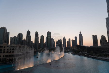 Téléchargez les photos : Dubaï chantant fontaines à la nuit vue sur le lac entre les gratte-ciel. Skyline de la ville au crépuscule architecture moderne dans la capitale des Émirats arabes unis centre-ville. Images 4k de haute qualité - en image libre de droit