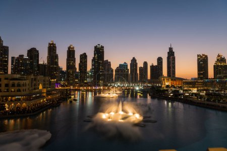 Foto de Dubai cantando fuentes en vista al lago nocturno entre rascacielos. Ciudad horizonte en la arquitectura moderna del atardecer en la capital de los Emiratos Árabes Unidos centro. Imágenes de alta calidad 4k - Imagen libre de derechos