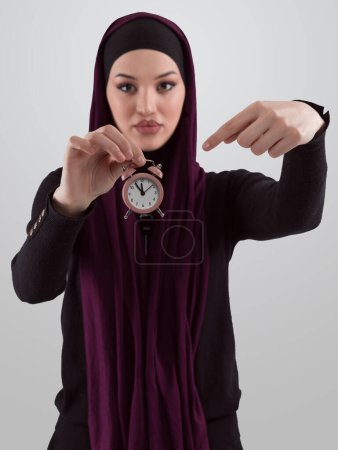 Téléchargez les photos : Beautiful arab businesswoman wearing hijab and holding a small clock. Time is passing and its a pressure concept. High quality photo - en image libre de droit