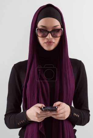 Téléchargez les photos : Woman in black stylish fashionable clothes Muslim headscarf. Lady using smart phone, close up portrait of smiling middle eastern girl. High quality photo - en image libre de droit