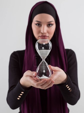 Photo for Beautiful arab businesswoman wearing hijab and holding sand clock. Time is passing and its a pressure concept. High quality photo - Royalty Free Image