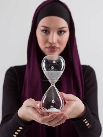 Foto de Beautiful arab businesswoman wearing hijab and holding sand clock. Time is passing and its a pressure concept. High quality photo - Imagen libre de derechos