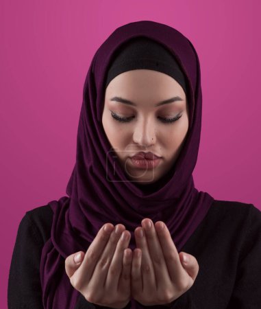 Téléchargez les photos : Muslim woman in hijab and traditional clothes praying for Allah, copy space. Muslim woman with hijab praying indoor pink background. High quality photo - en image libre de droit