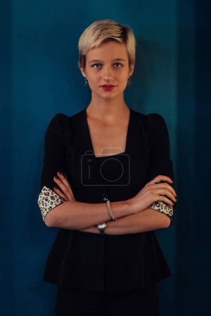 Foto de Blonde business woman, successful confidence with arms crossed on modern blue mat background. Selective focus. - Imagen libre de derechos