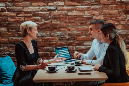 Foto de Happy businesspeople smiling cheerfully during a meeting in a coffee shop. Group of successful business professionals working as a team in a multicultural workplace. - Imagen libre de derechos