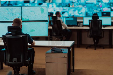 Photo for Group of Security data center operators working in a CCTV monitoring room looking on multiple monitors.Officers Monitoring Multiple Screens for Suspicious Activities. - Royalty Free Image