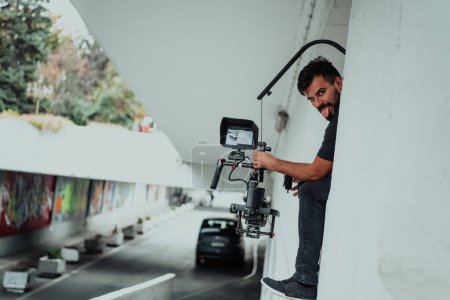Téléchargez les photos : A professional cameraman with equipment and a stabilizer recoding two woman for a commercial advertisement as they run in an urban environment. - en image libre de droit