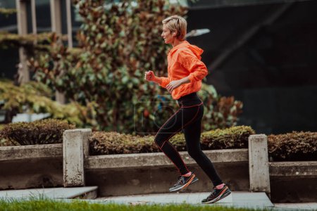 Photo for A blonde in a sports outfit is running around the city in an urban environment. The hot blonde maintains a healthy lifestyle - Royalty Free Image