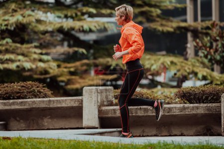Téléchargez les photos : A blonde in a sports outfit is running around the city in an urban environment. The hot blonde maintains a healthy lifestyle - en image libre de droit