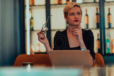 Foto de Businesswoman sitting in a cafe while focused on working on a laptop and participating in an online meetings. Selective focus - Imagen libre de derechos