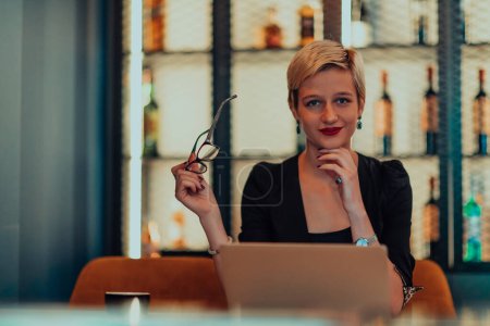 Geschäftsfrau sitzt in einem Café, während sie konzentriert an einem Laptop arbeitet und an einem Online-Meeting teilnimmt. Selektiver Fokus