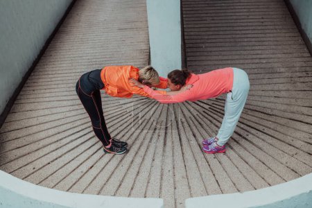 Téléchargez les photos : Deux femmes se réchauffent ensemble et se préparent à une course matinale dans un environnement urbain. Concentration sélective . - en image libre de droit