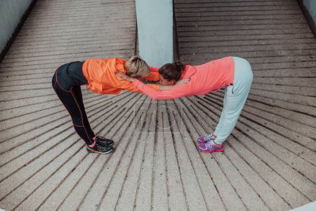 Téléchargez les photos : Two women warming up together and preparing for a morning run in an urban environment. Selective focus . - en image libre de droit