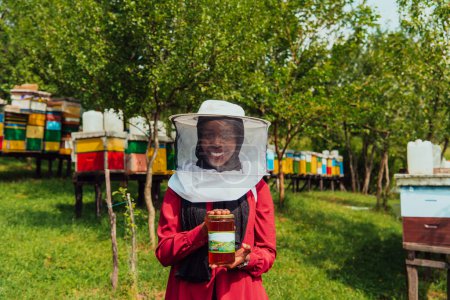 Téléchargez les photos : Portrait of Arab investitor in the beekeeping department of a honey farm holding a jar of honey in her hand. - en image libre de droit