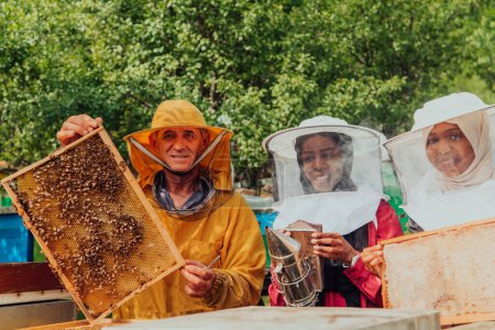 Foto de Arab investors checking the quality of honey on a large bee farm in which they have invested their money. The concept of investing in small businesses. - Imagen libre de derechos