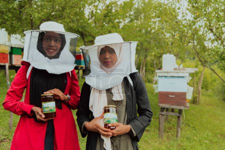 Téléchargez les photos : Portrait of an Arab investors holding a jar of honey in their hands while standing in front of a large honey farm. The concept of investing in small businesses. - en image libre de droit