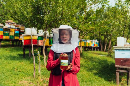 Photo for Portrait of Arab investitor in the beekeeping department of a honey farm holding a jar of honey in her hand. - Royalty Free Image