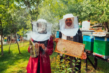 Foto de Arab investors checking the quality of honey on a large honey farm in which they invested their money. The concept of investing in small businesses. - Imagen libre de derechos