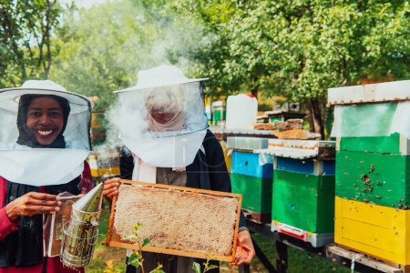 Foto de Inversores árabes comprobando la calidad de la miel en una gran granja de miel en la que invirtieron su dinero. Concepto de inversión en pequeñas empresas. - Imagen libre de derechos
