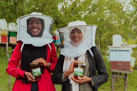 Téléchargez les photos : Portrait of an Arab investors holding a jar of honey in their hands while standing in front of a large honey farm. The concept of investing in small businesses. - en image libre de droit