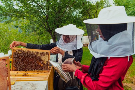 Téléchargez les photos : Arab investors check ingthe quality of honey on the farm in which they invested the money. Investing in small businesses - en image libre de droit