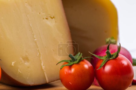 Foto de Bosnian traditional cheese served on a wooden container with peppers, parade and onions isolated on a white background. - Imagen libre de derechos