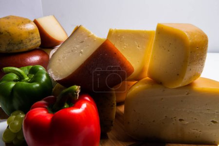 Photo for Bosnian traditional cheese served on a wooden container with peppers, parade and onions isolated on a white background. - Royalty Free Image