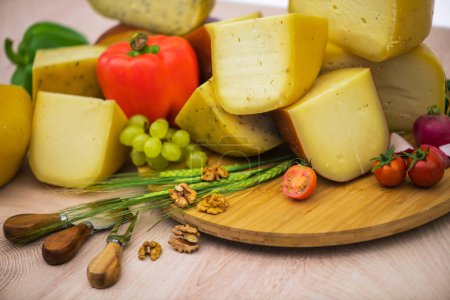 Foto de Bosnian traditional cheese served on a wooden container with peppers, parade and onions isolated on a white background. - Imagen libre de derechos