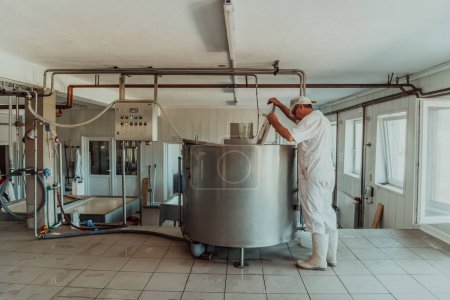 Photo for Man mixing milk in the stainless tank during the fermentation process at the cheese manufacturing. - Royalty Free Image