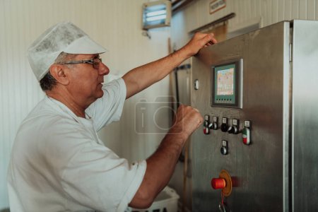 Foto de Fabricante de queso que trabaja en la industria moderna en máquinas que utilizan para el mecanizado de queso fresco. - Imagen libre de derechos