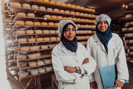 Foto de Arab business partners checking the quality of cheese in the industry and enter data into a laptop. Small business concept. - Imagen libre de derechos