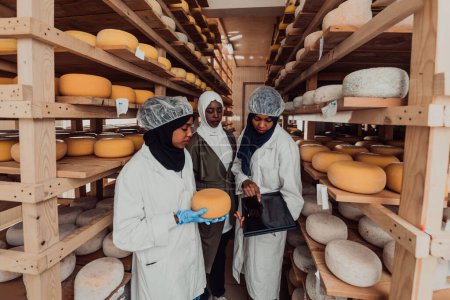 Téléchargez les photos : Les partenaires commerciaux arabes vérifient la qualité du fromage dans l'industrie et saisissent les données dans un ordinateur portable. Concept de petite entreprise. - en image libre de droit