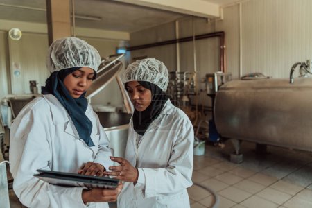 Téléchargez les photos : Les partenaires commerciaux arabes vérifient la qualité du fromage dans l'industrie et saisissent les données dans un ordinateur portable. Concept de petite entreprise. - en image libre de droit
