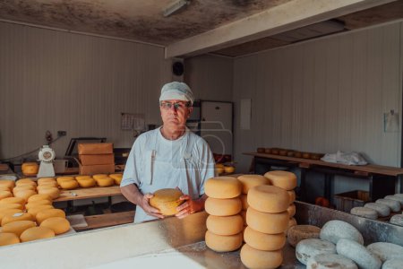 Téléchargez les photos : The cheese maker sorting freshly processed pieces of cheese and preparing them for the further processing process. - en image libre de droit