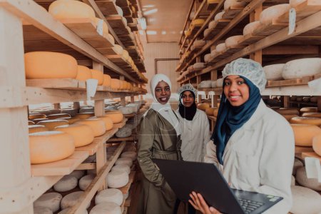 Téléchargez les photos : Arab business partners checking the quality of cheese in the industry and enter data into a laptop. Small business concept. - en image libre de droit