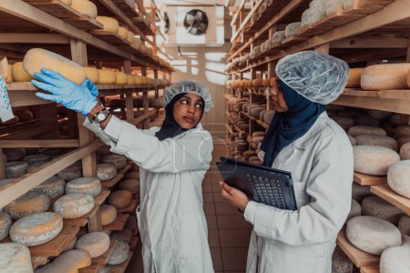 Foto de Socios comerciales árabes que verifican la calidad del queso en la industria e introducen datos en una computadora portátil. Concepto de pequeña empresa. - Imagen libre de derechos