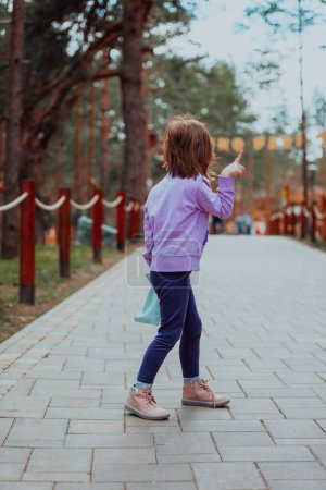 Photo for A little girl playing in the park. The concept of family socializing in the park. A girl swings on a swing, plays creative games. - Royalty Free Image