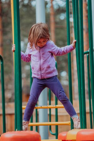 Foto de A little girl playing in the park. The concept of family socializing in the park. A girl swings on a swing, plays creative games. - Imagen libre de derechos