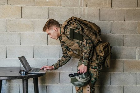 Photo for American soldier in military uniform using laptop computer for drone controlling and to stay in contact with friends and family. - Royalty Free Image