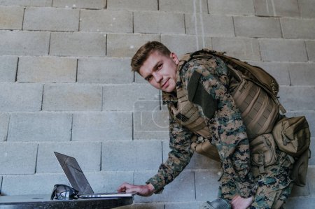 Foto de Soldado estadounidense en uniforme militar usando computadora portátil para el control de drones y para mantenerse en contacto con amigos y familiares. - Imagen libre de derechos
