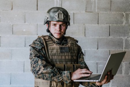 Téléchargez les photos : Soldat américain en uniforme militaire utilisant un ordinateur portable pour contrôler les drones et rester en contact avec ses amis et sa famille. - en image libre de droit