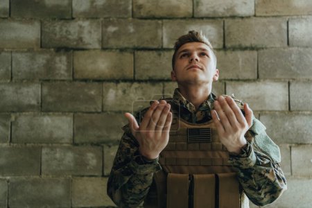 Foto de Un soldado musulmán de las fuerzas especiales ora a Dios levantando las manos y comienza una oración. - Imagen libre de derechos