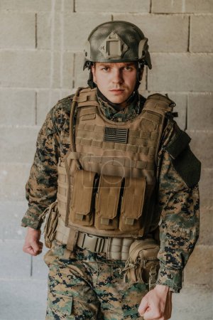 Téléchargez les photos : Un soldat en uniforme se tient devant un mur de pierre en équipement de guerre complet se préparant pour la bataille. - en image libre de droit