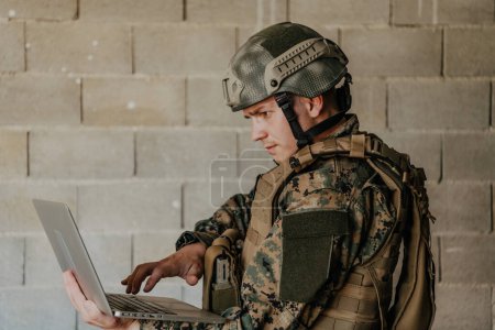 Téléchargez les photos : Soldat américain en uniforme militaire utilisant un ordinateur portable pour contrôler les drones et rester en contact avec ses amis et sa famille. - en image libre de droit