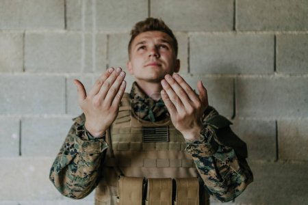 Photo for A Muslim soldier of the special forces prays to God by raising his hands and starts a prayer. - Royalty Free Image