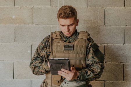 Téléchargez les photos : Soldat utilisant un ordinateur tablette contre un vieux mur de briques. - en image libre de droit