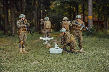 Foto de El escuadrón de soldados de guerra moderna está usando aviones no tripulados para explorar y vigilar durante la operación militar en el bosque - Imagen libre de derechos
