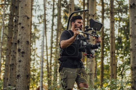 Téléchargez les photos : Vidéographe avec caméra vidéo professionnelle Gimbal Stabiliser l'équipement Passons à l'action Tirer sur les soldats en action dans la forêt. - en image libre de droit