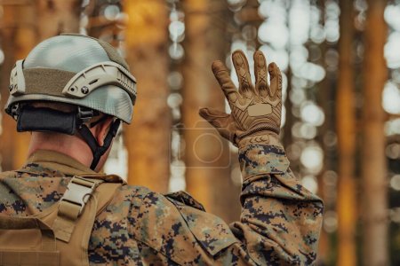 moderner Soldat zeigt taktische Handsignale, um lautlos Befehle zu erteilen und die Umgebung des Truppenteams zu erforschen.